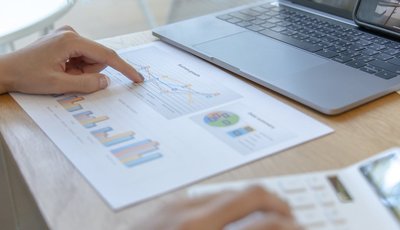 persona revisa unos documentos financieros, mientras hace cálculos con ayuda de una calculadora